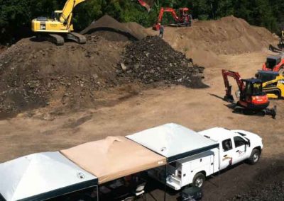 A truck is parked in the dirt near some construction equipment.