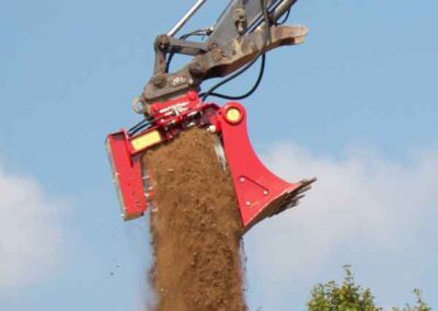 A red machine is digging dirt on the ground.